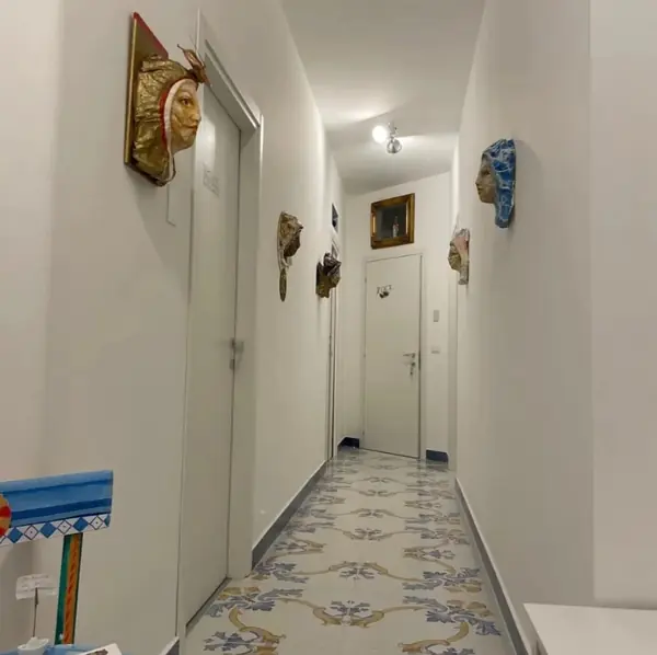 Corridoio con pavimento in maiolica e maschere artistiche alle pareti
