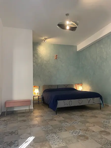 Camera del bilocale Sicilia con pavimento in cementine e lampada a specchio